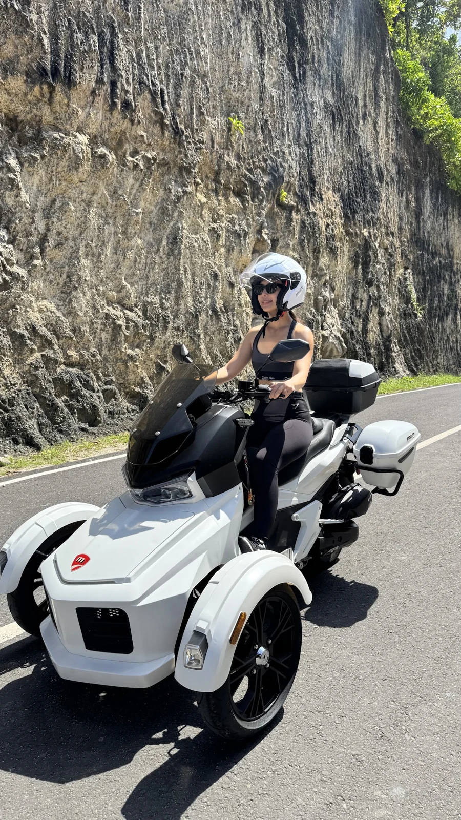Woman wearing a helmet on a white Moratti beside a cliff